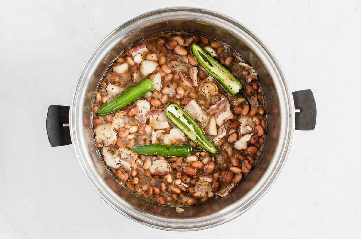 Jalapeños, onions and pinto beans in a pot.