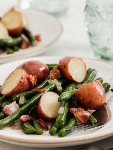 White plate with sautéed green beans and red new potatoes.