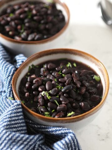 Two bowls of black beans with napkin on the side.
