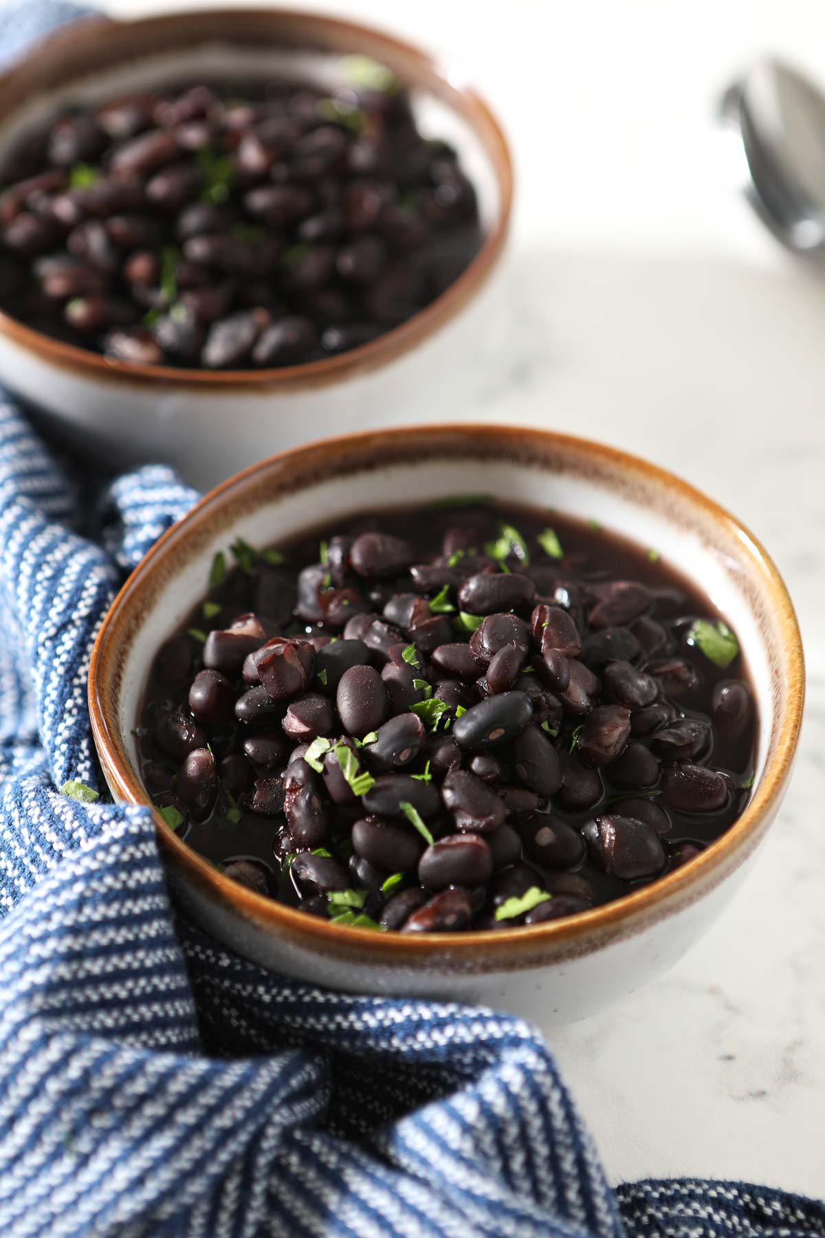 Two bowls of black beans with napkin on the side.