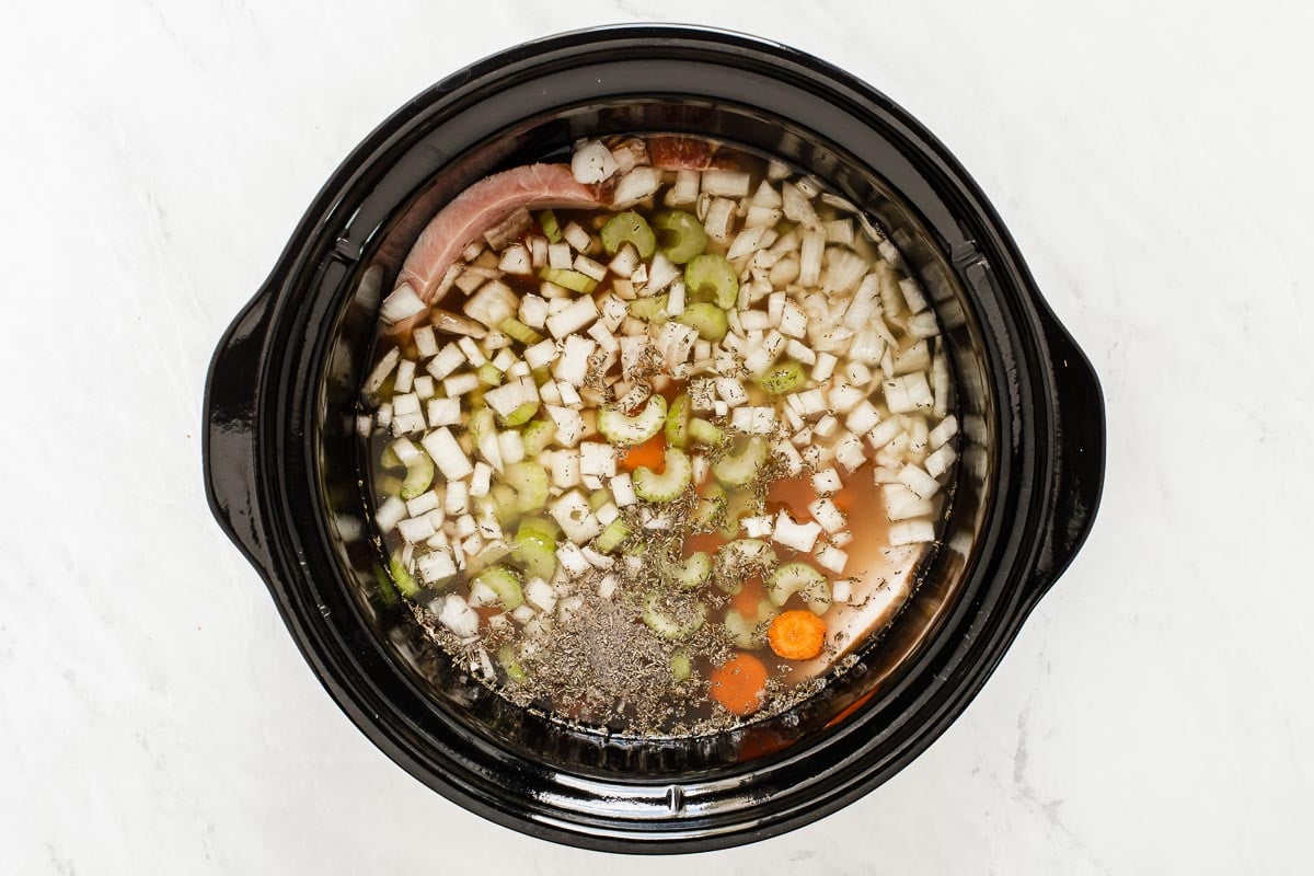 Adding spices and chicken broth to a slow cooker.
