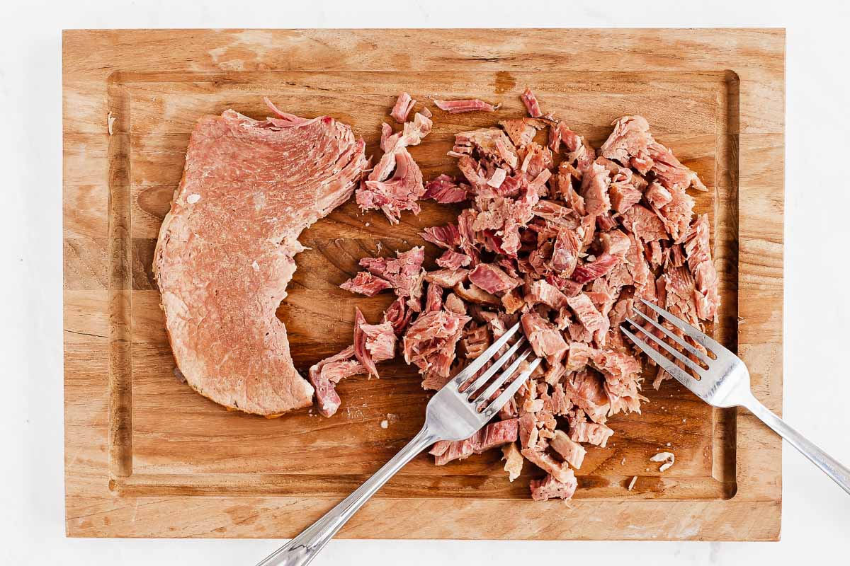 Shredding a ham steak on a cutting board.