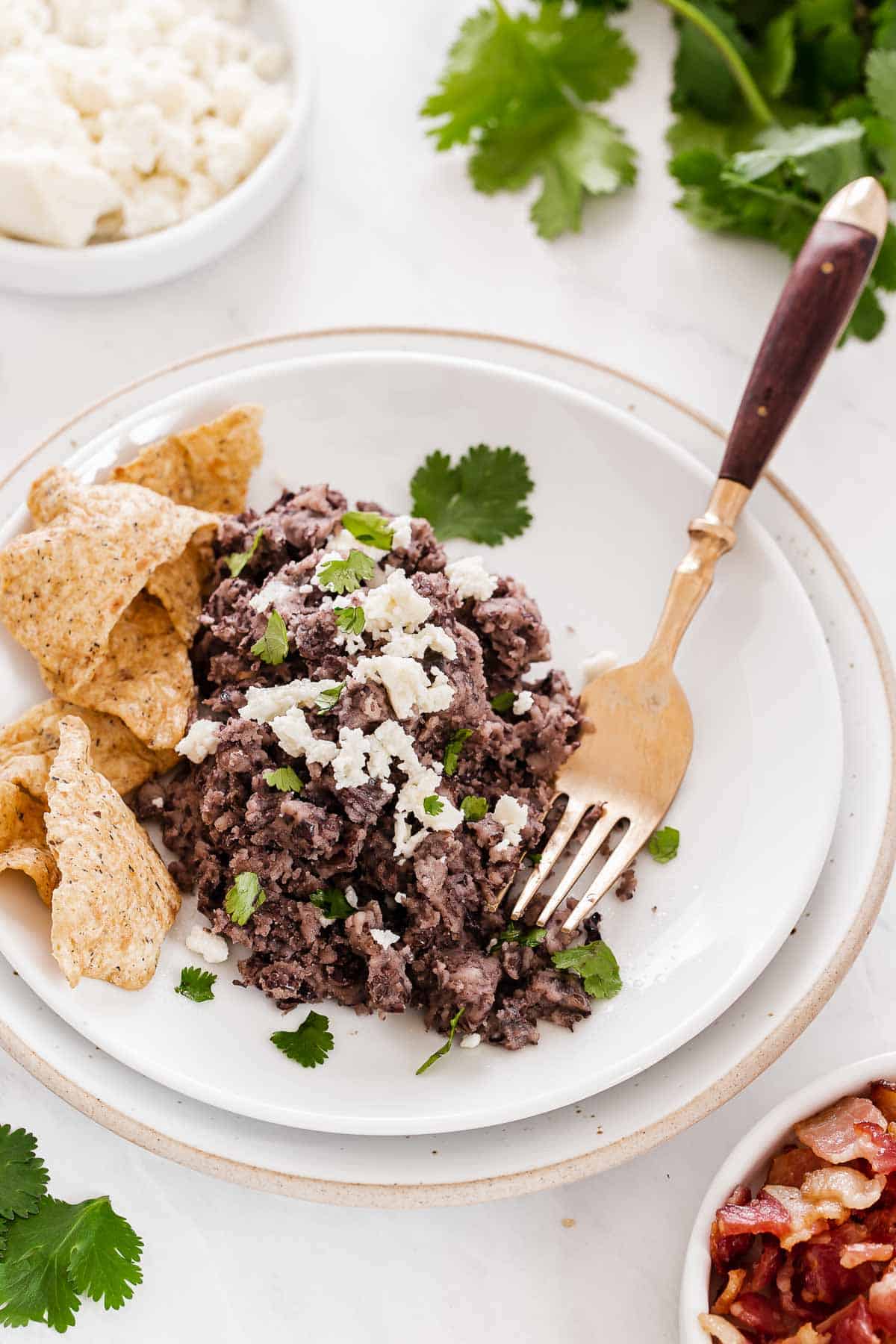 White plate with refried black beans and chips.