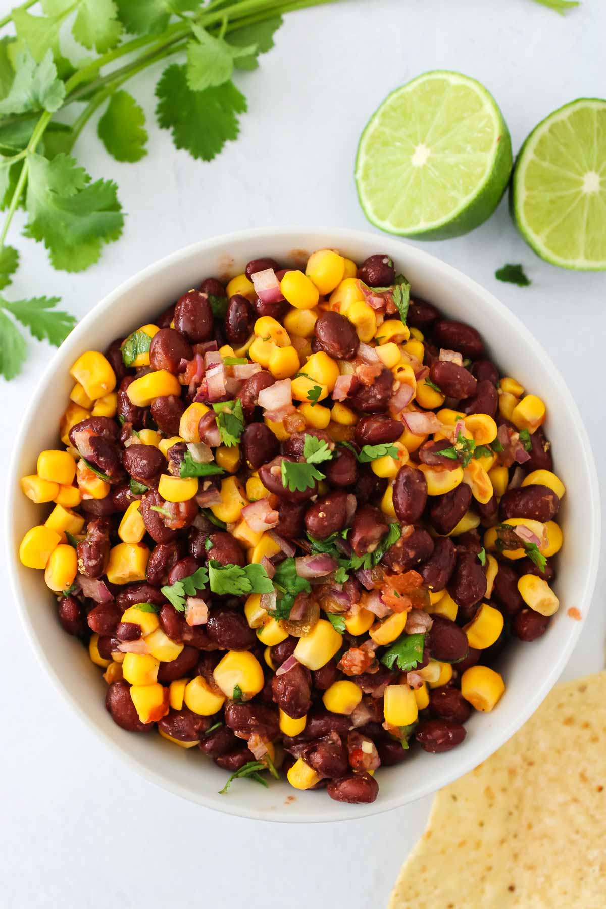 Black bean and corn salsa in white bowl with cilantro on side.