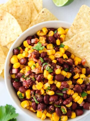 Bowl of black bean and corn salad with tortilla chips for dipping.