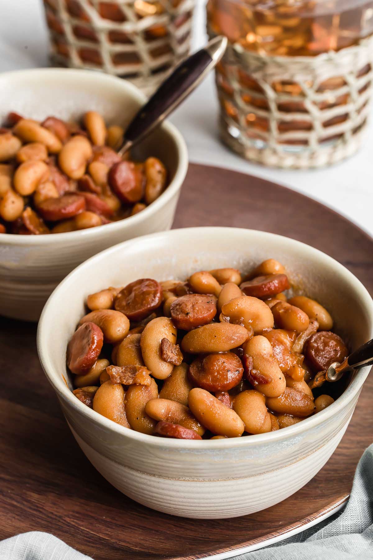 Pork and beans in white bowls with spoon.