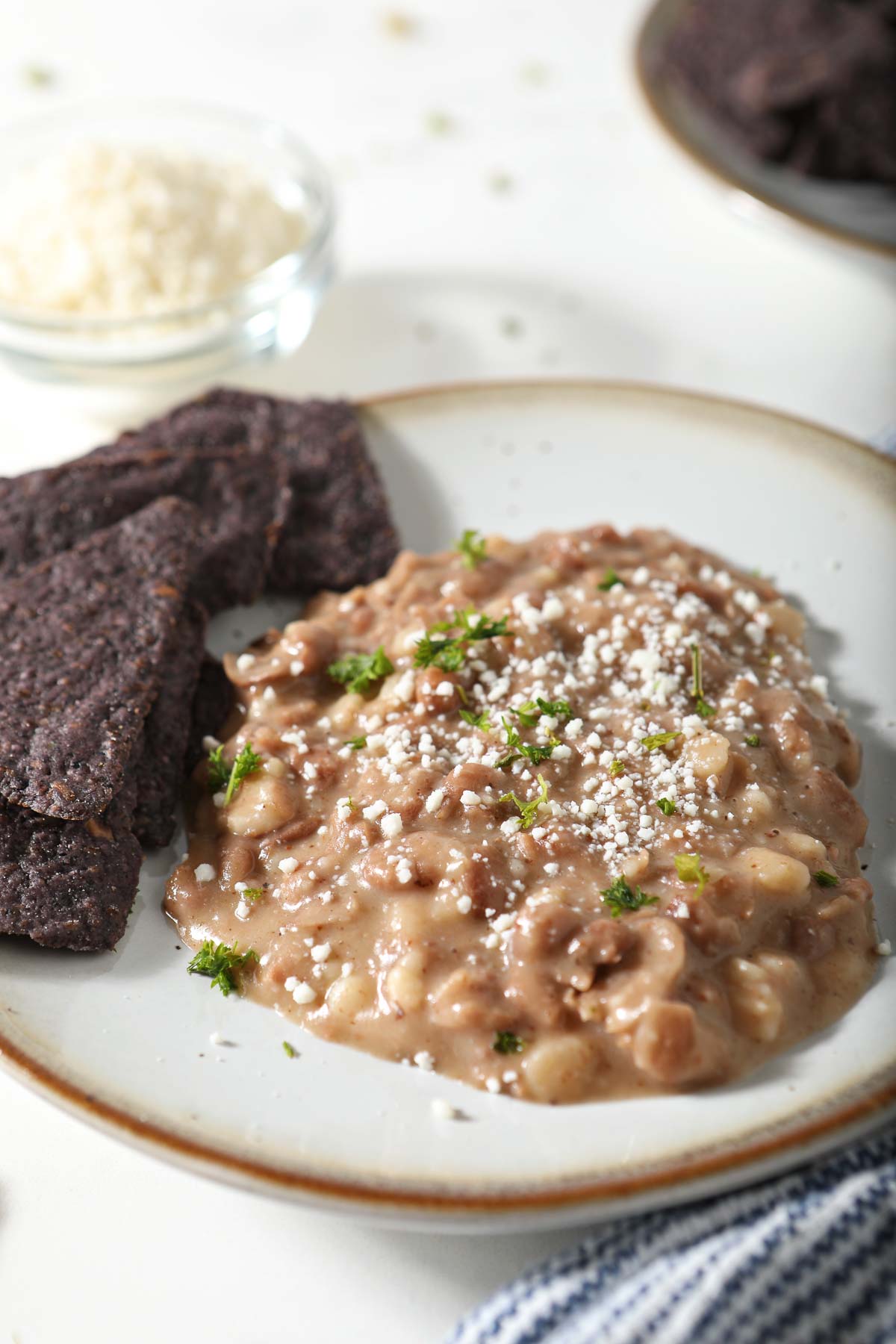 Refried beans on plate with blue corn tortilla chips.