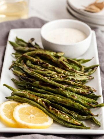 Roasted green beans with ranch on the side.