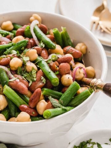 White bowl of three bean salad with serving fork.