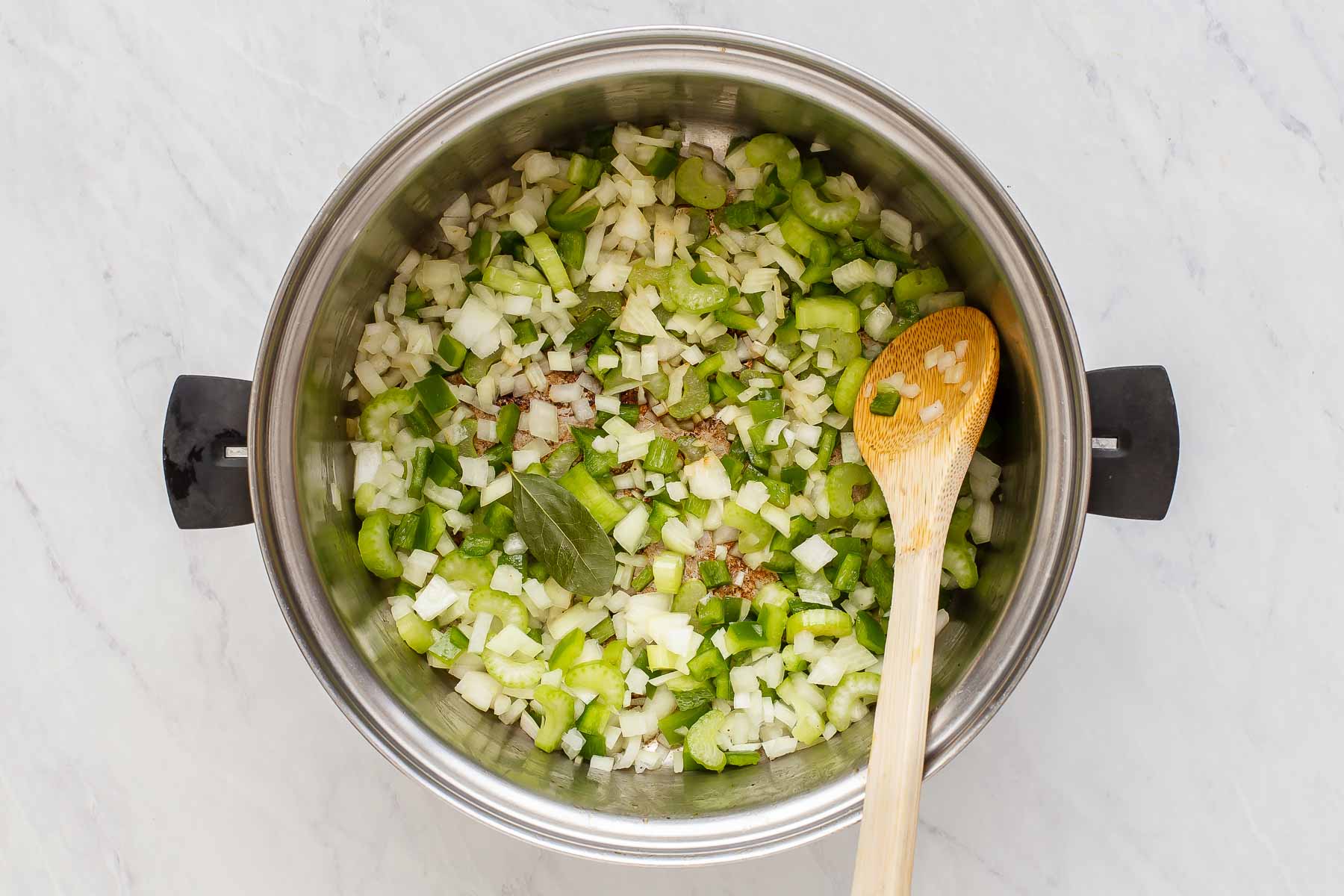 Onions, celery and green bell pepper cooking in sauce pot.