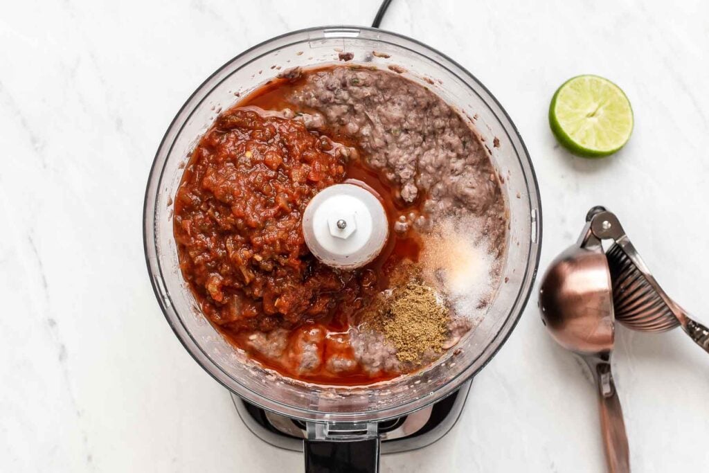 Salsa and spices in food processor with bean dip.