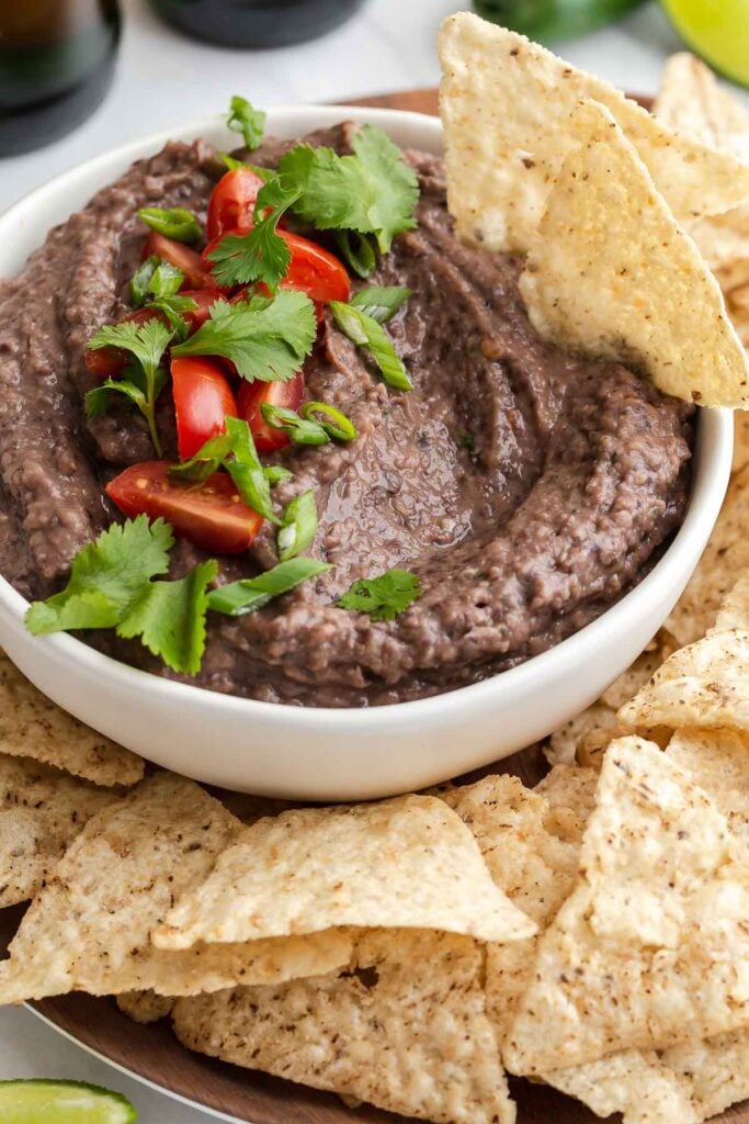 Bowl of bean dip with chips and cilantro garnish.