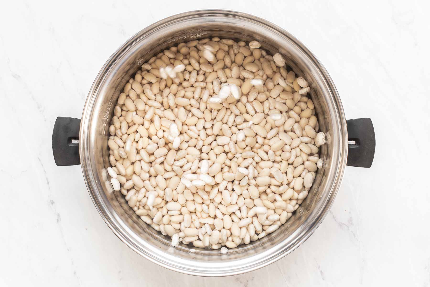 White beans soaking in water in pan.
