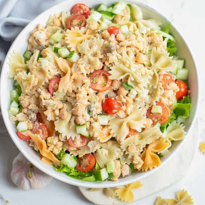 Chickpea pasta salad in white bowl with blue napkin.
