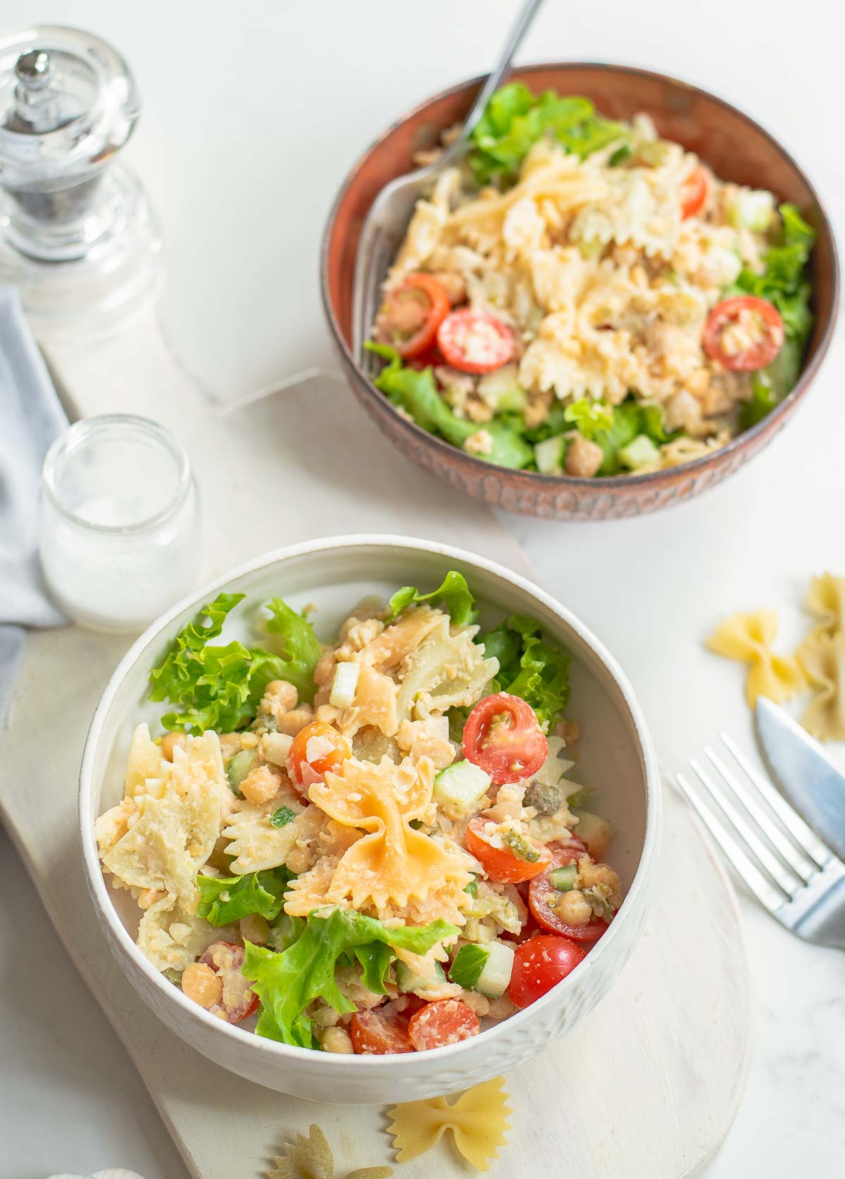 Pasta salad with chickpeas in two bowl with forks.