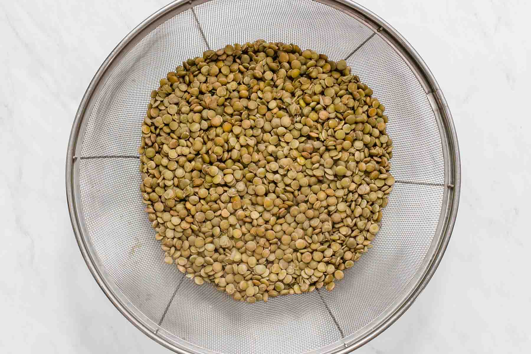 Cooked lentils, draining in colander.
