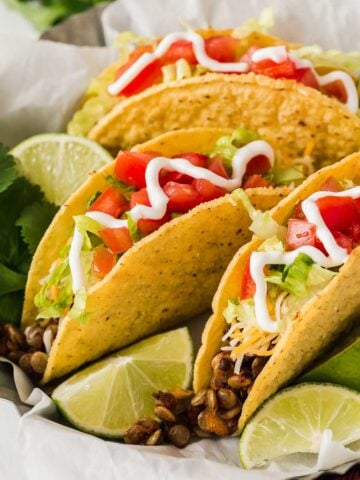 Three crunchy tacos on a plate with lentil taco meat filling.