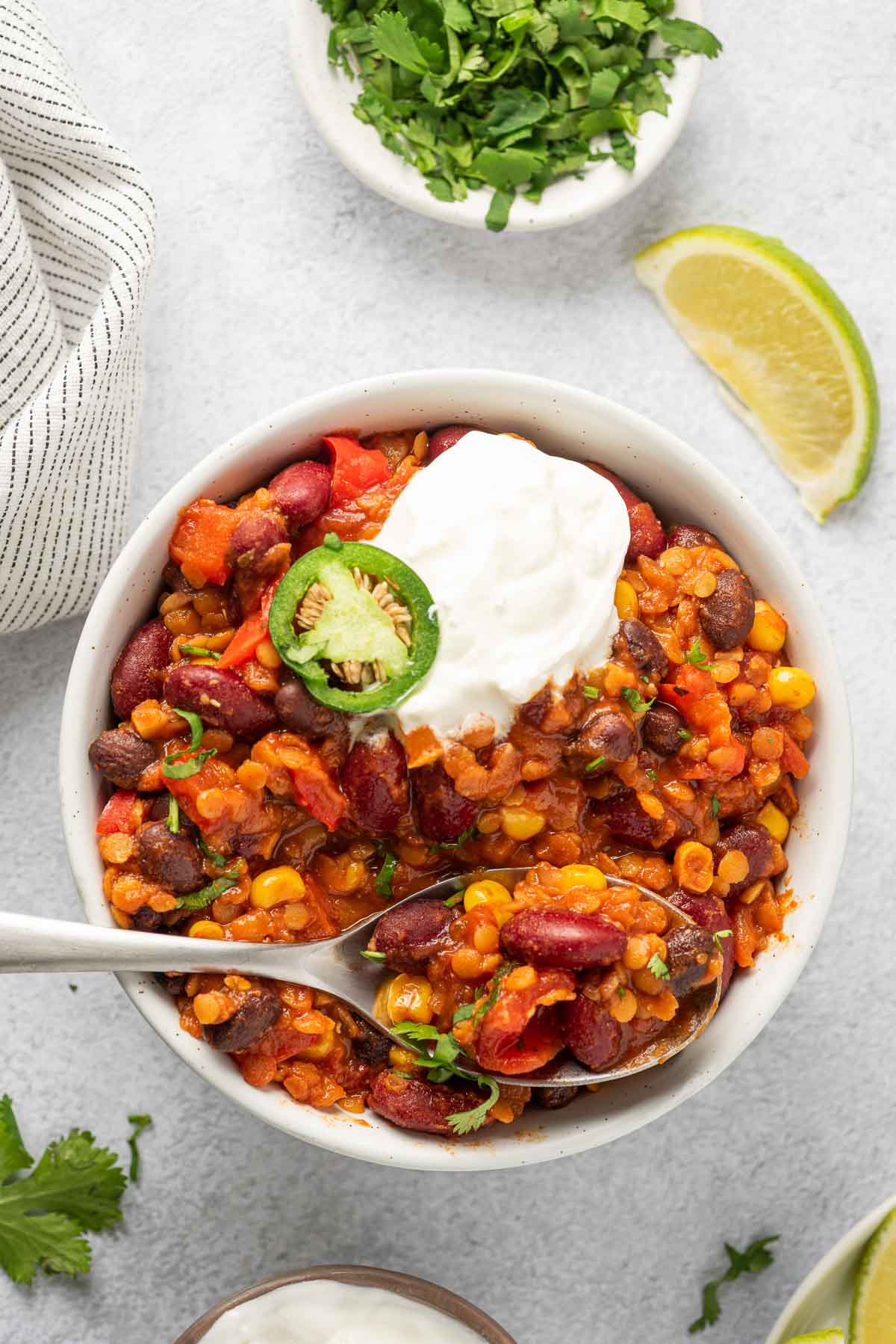 Bowl of red lentil chili with spoon and sour cream.