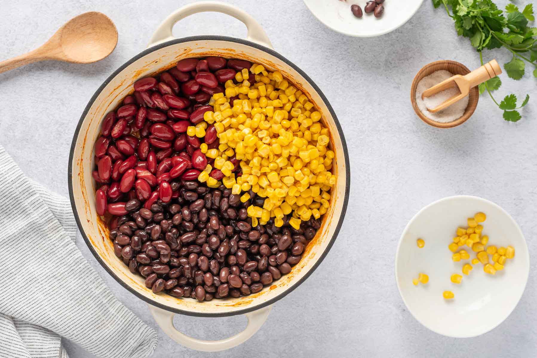Kidney beans, black beans and corn adding to pot of chili.