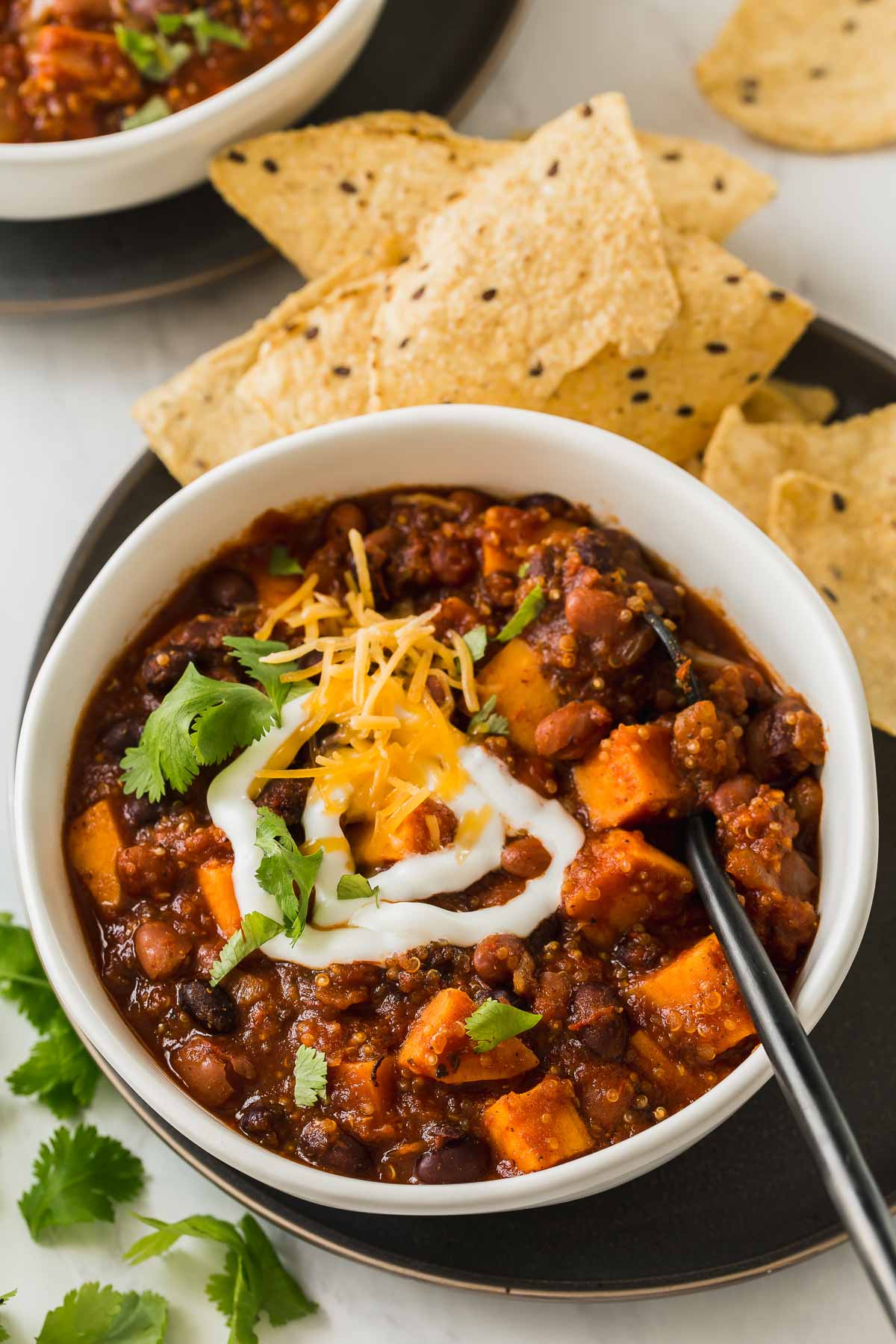 Bowl of chili with spoon and tortilla chips on side.