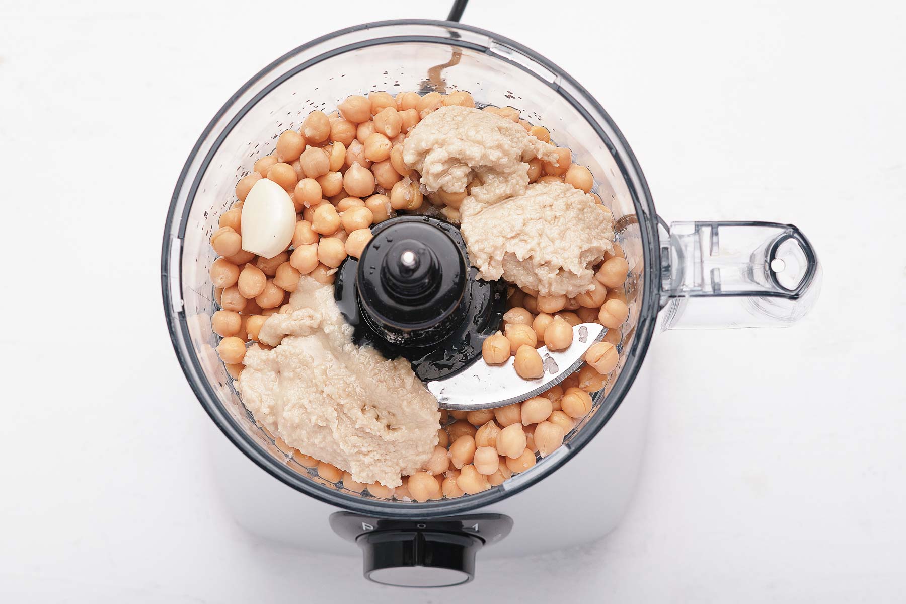 Ingredients for hummus in a food processor bowl.