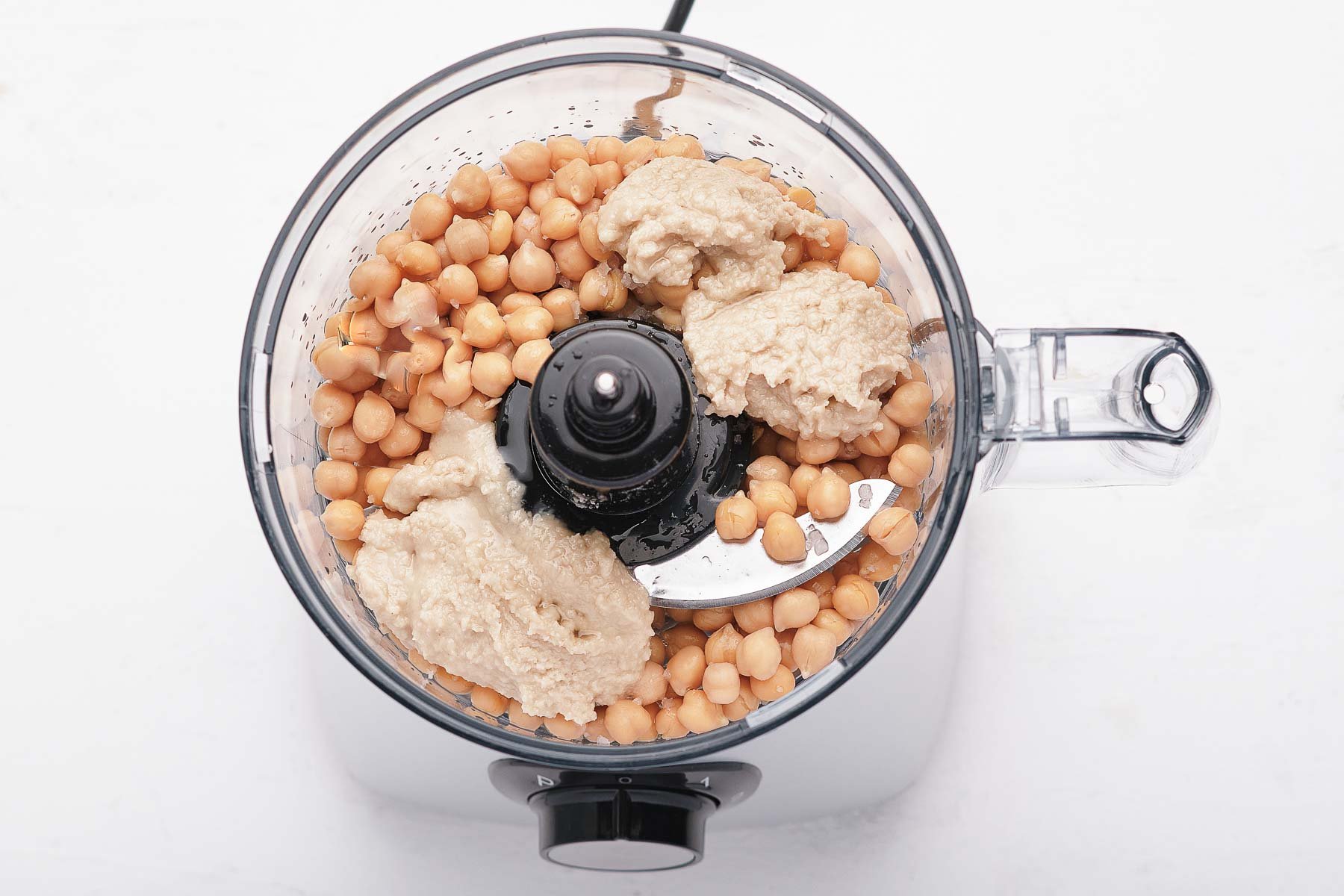 Chickpeas and tahini in a food processor bowl.