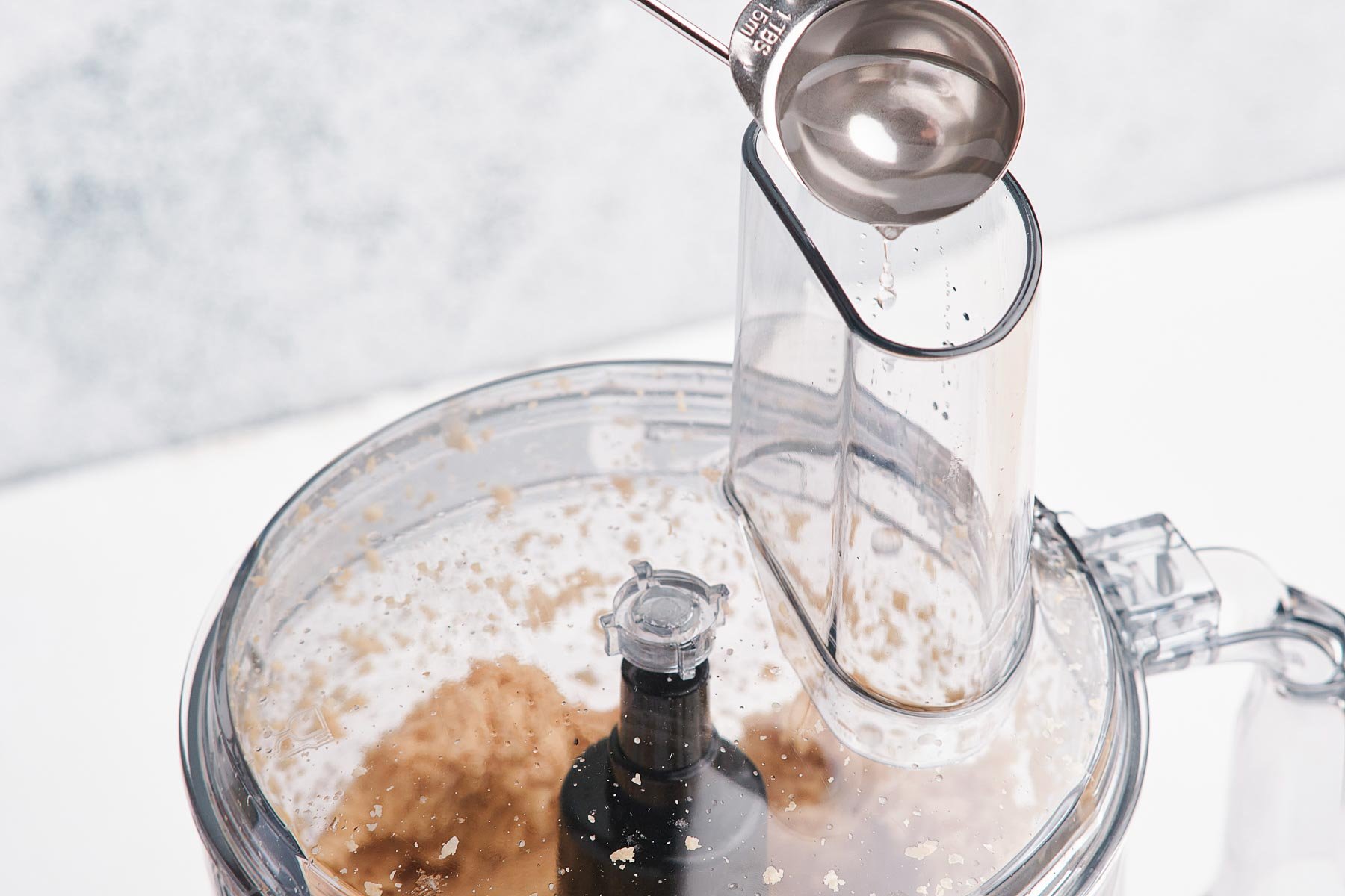 Pouring water into food processor spout.