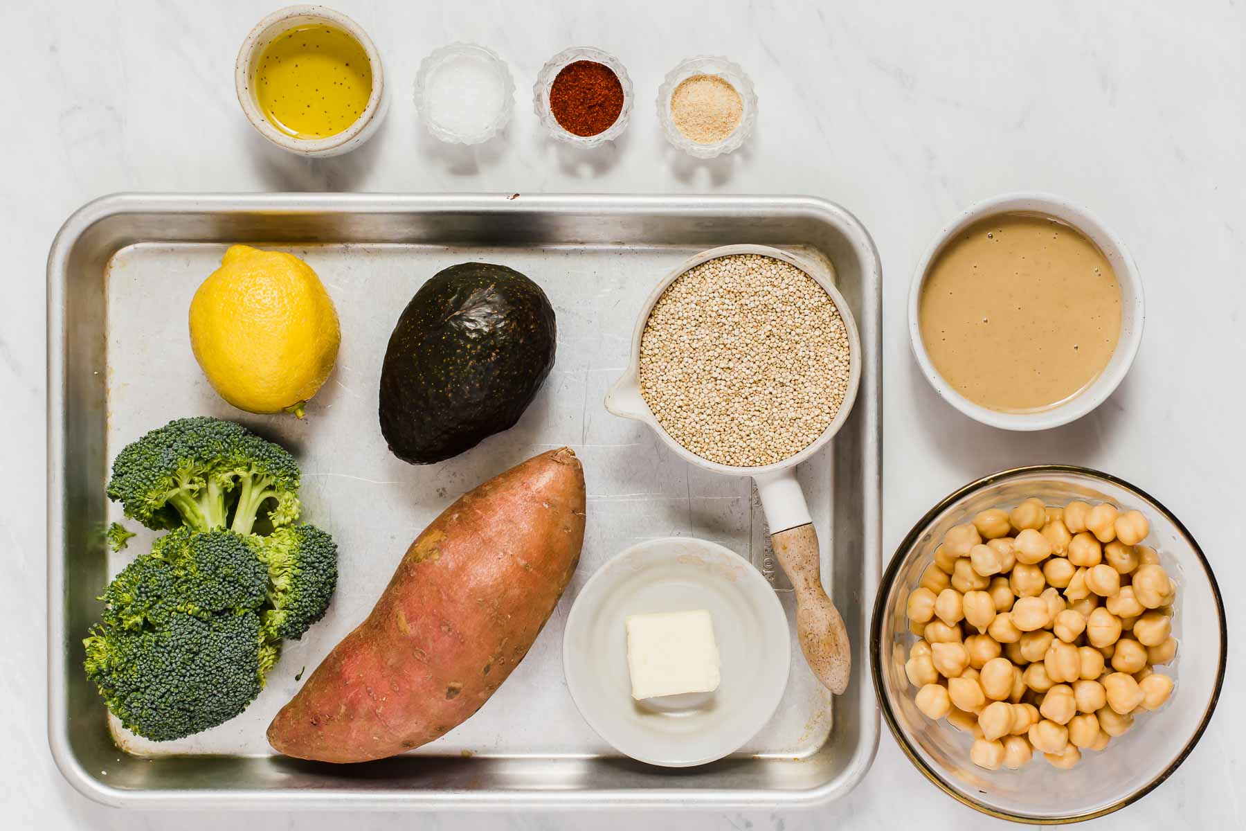 Sweet potato, broccoli, quinoa, chickpeas, and tahini on a sheet pan.