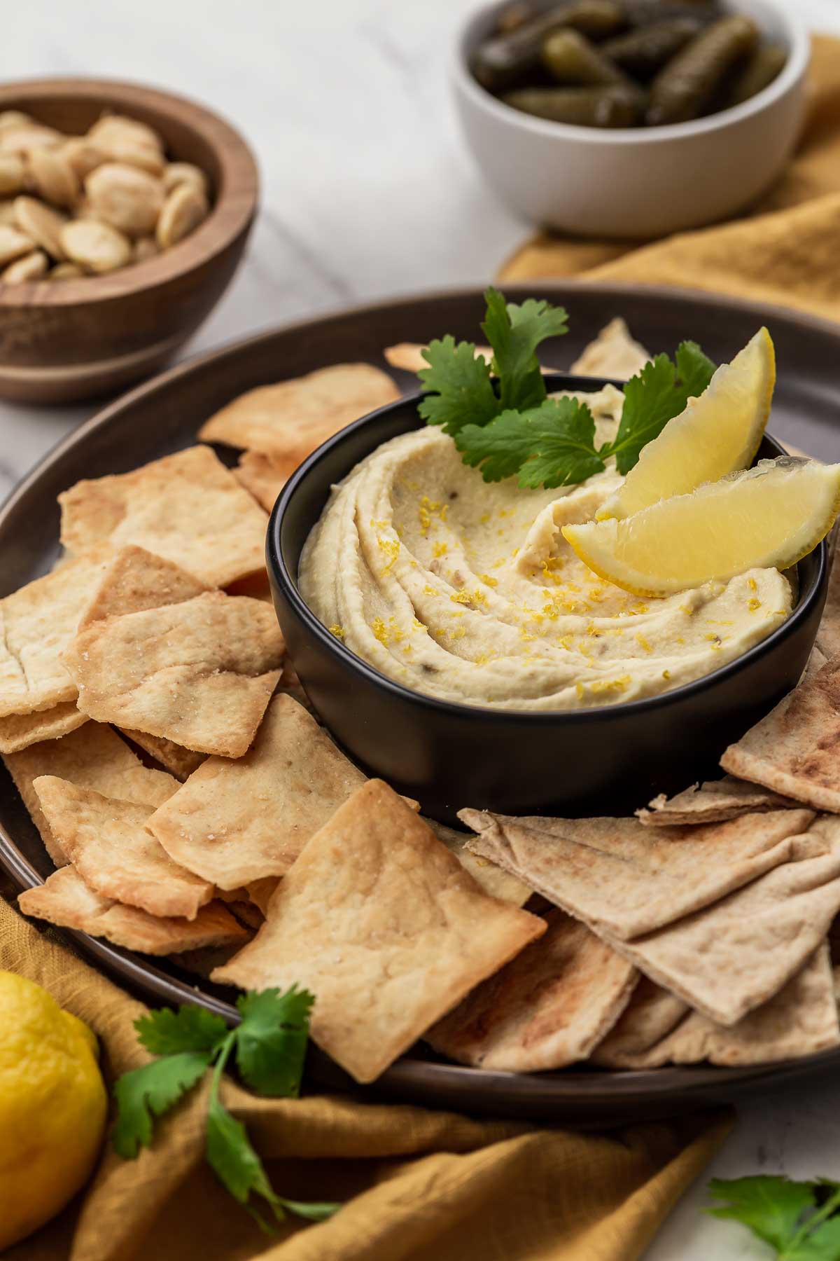 Platter with white butter bean dip and pita chips and nuts.