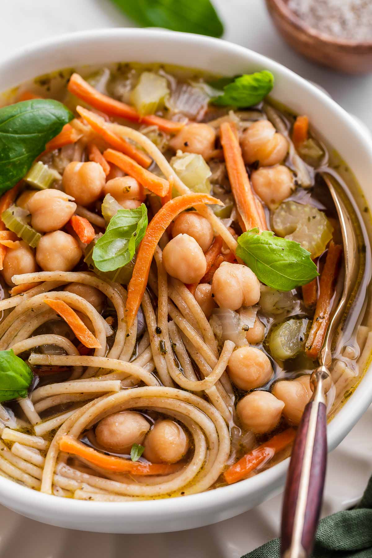 Close up of chickpea noodle soup bowl with spoon.