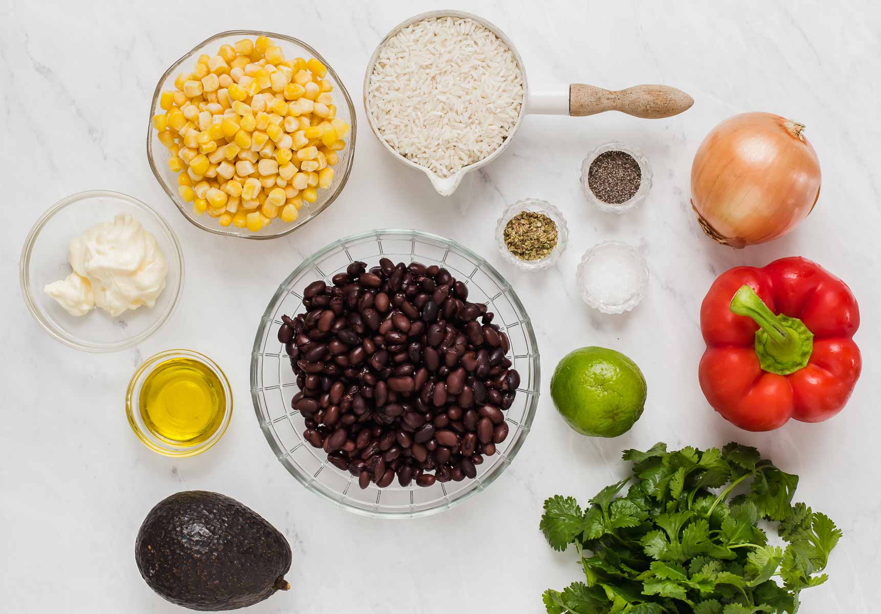 Black beans, corn, and salsa ingredients in bowls on white table.