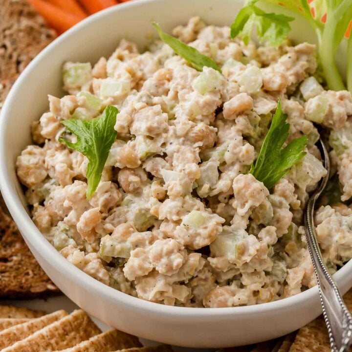 Chickpea tuna salad in white bowl with carrots flanking.