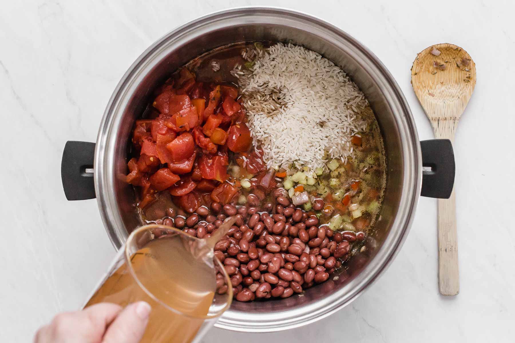 Adding beans, rice, tomatoes and broth to pot.