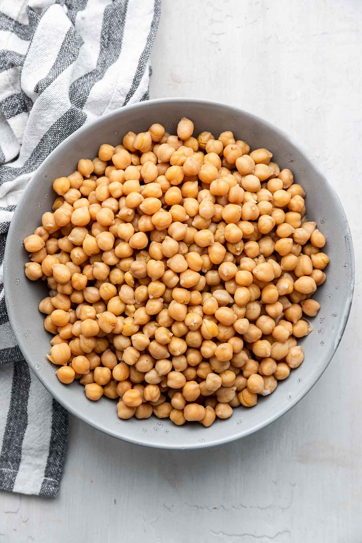 Overhead photo of instant pot chickpeas in a bowl with kitchen towel on the side.