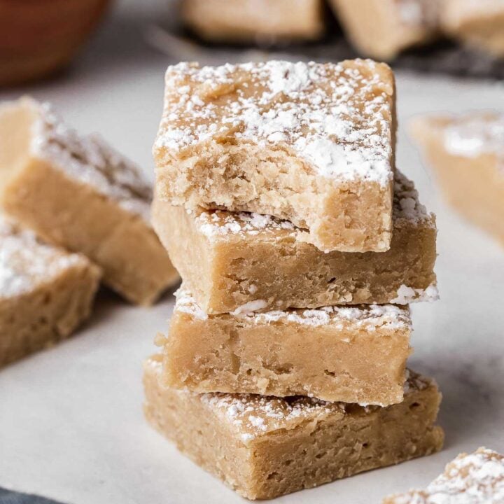Three white bean blondies stacked on top of each other with a bite missing.