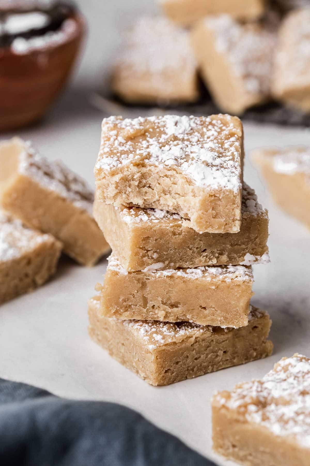 Three white bean blondies stacked on top of each other with a bite missing.