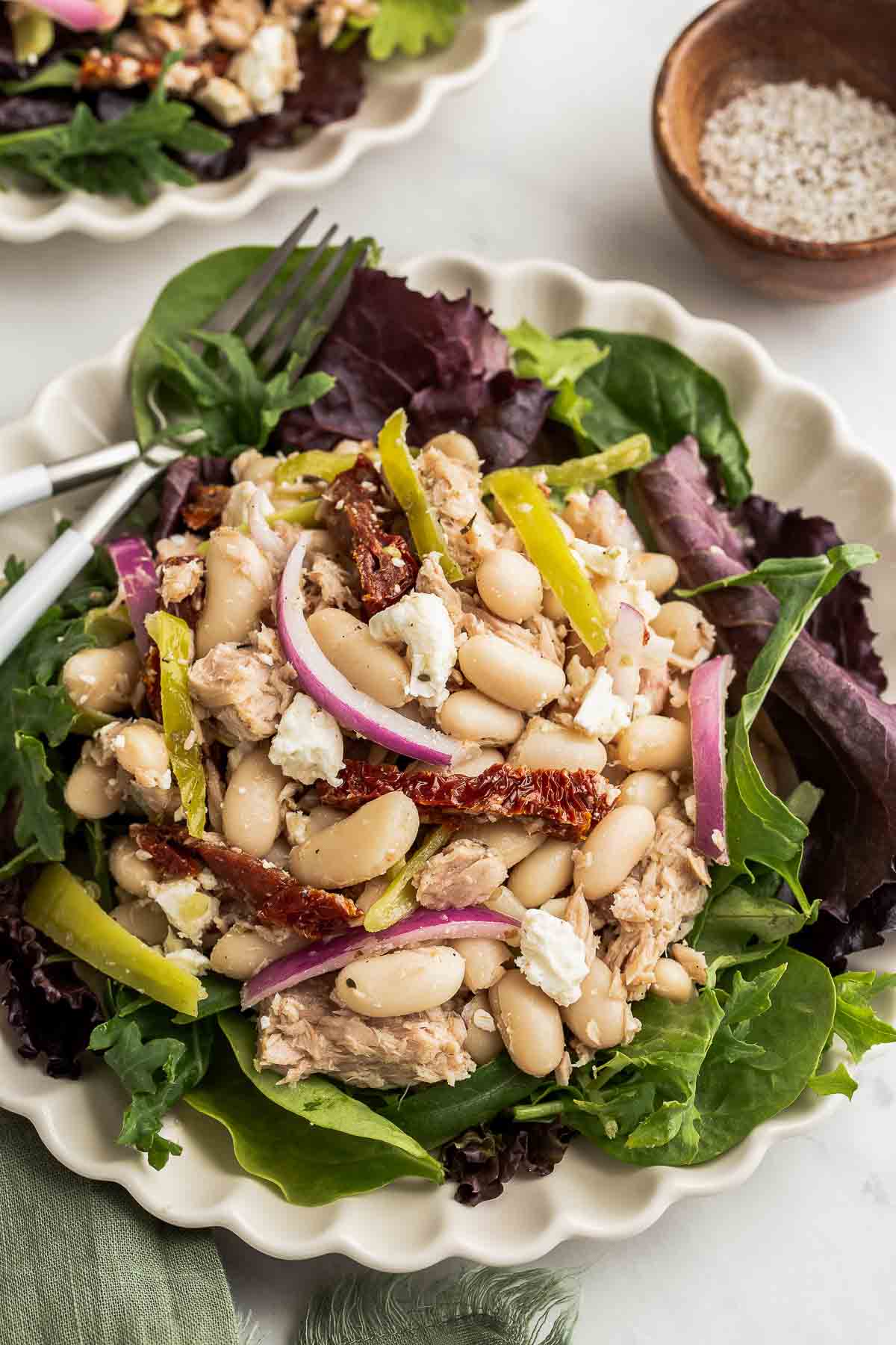 White bean tuna salad on plate over salad greens.