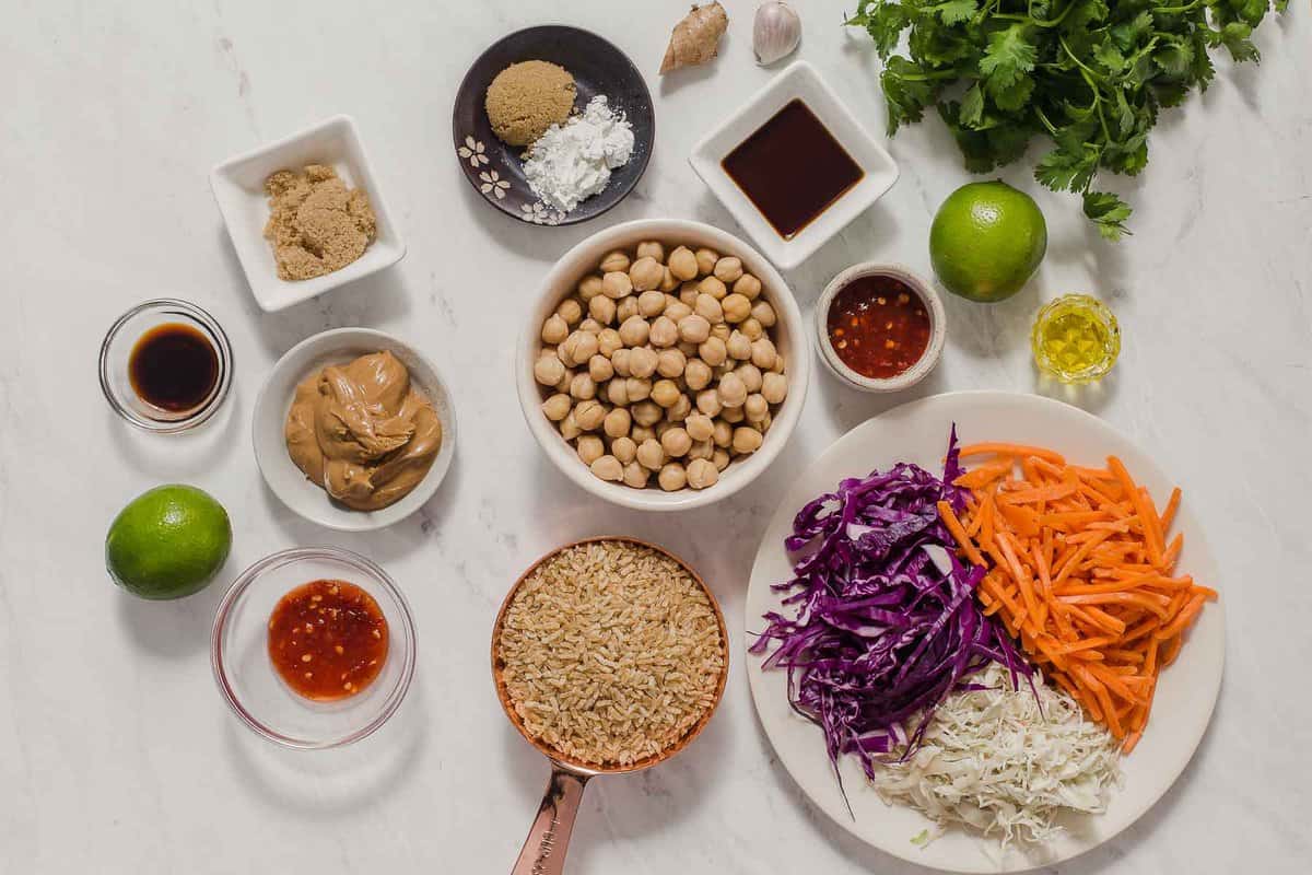 Ingredients to make chickpea bowls with fresh vegetables in small bowls on white table.