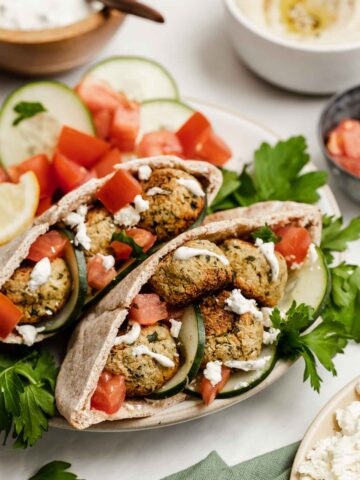 Pitas, split open and stuffed with baked falafel, cucumbers, tomatoes and drizzled with white sauce.