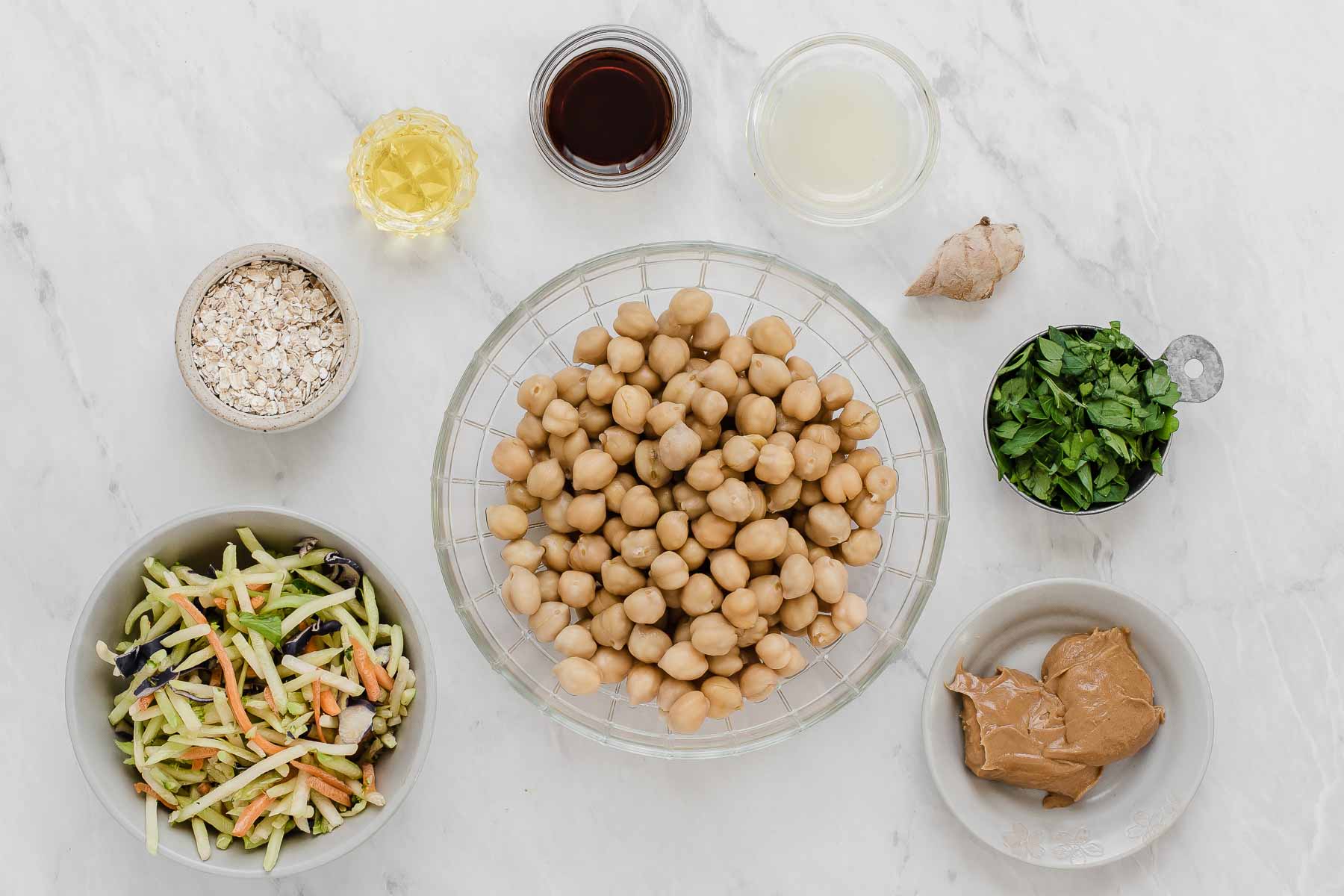 Chickpeas, broccoli slaw, peanut butter, and cilantro in small bowls on grey counter.