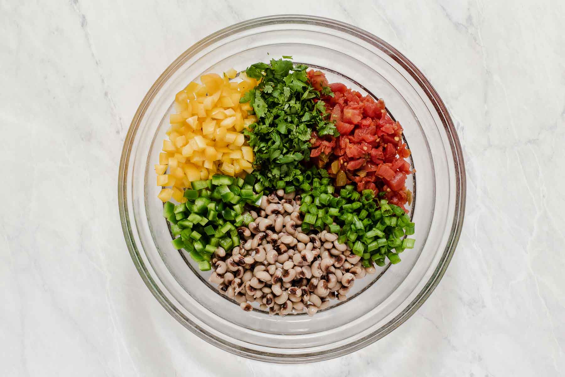 Bowl with chopped bell pepper, herbs, canned tomatoes and black eyed peas.
