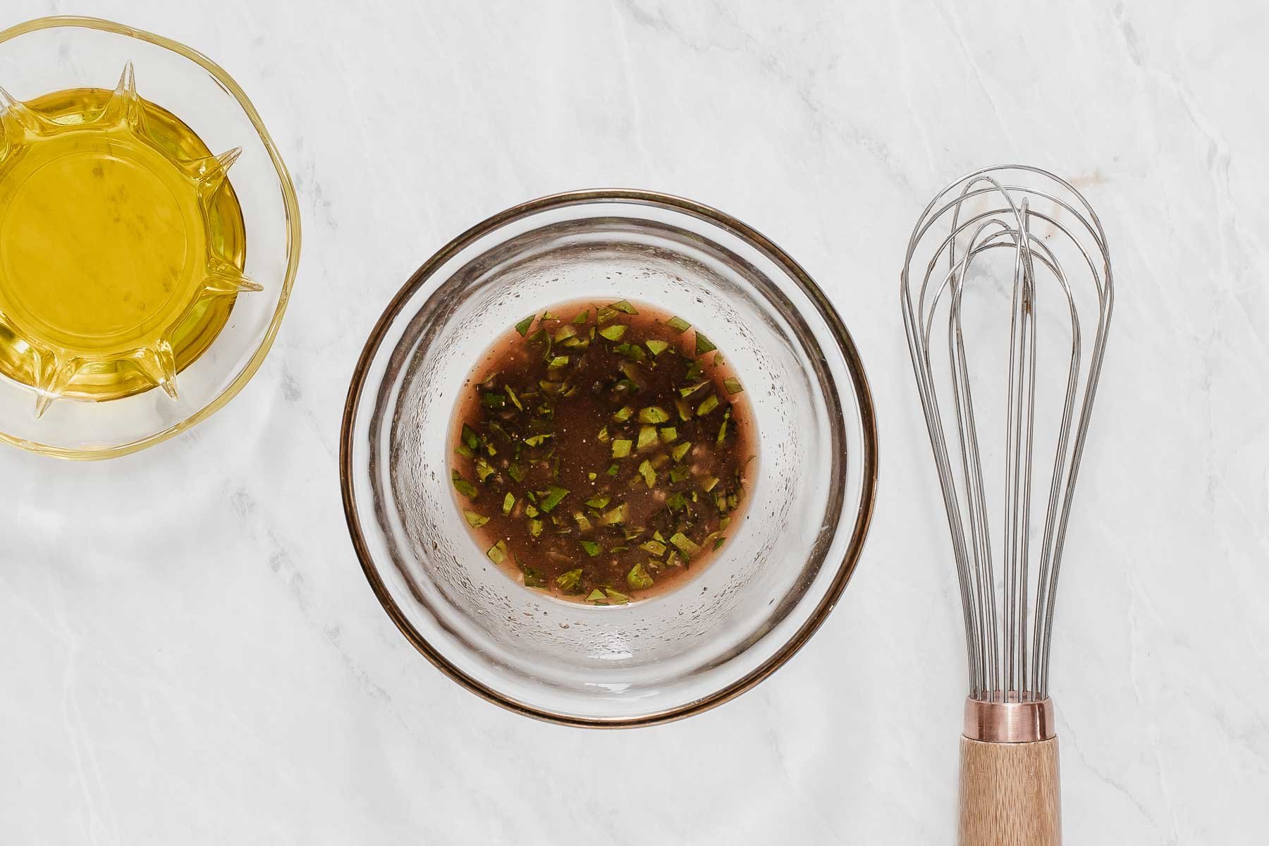 Brown vinaigrette in small bowl with whisk on the side.