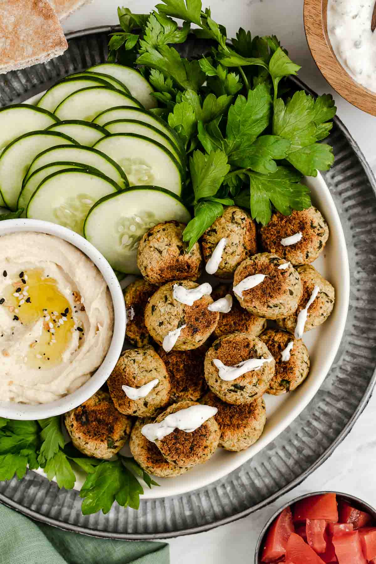 Vertical shot of plate with baked falafel, cucumbers and hummus dip.