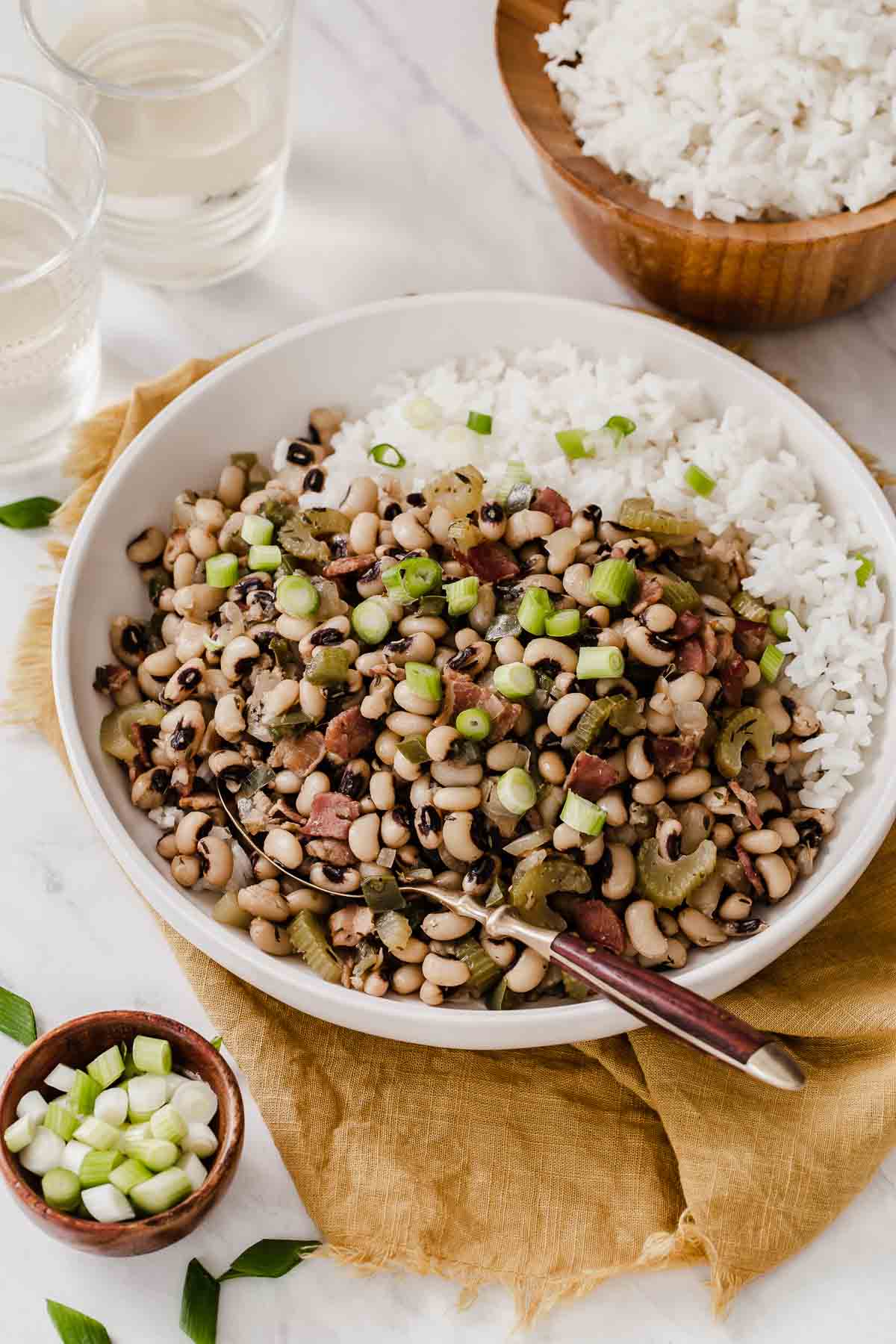 White bowl of Hoppin John with rice on side and spoon.