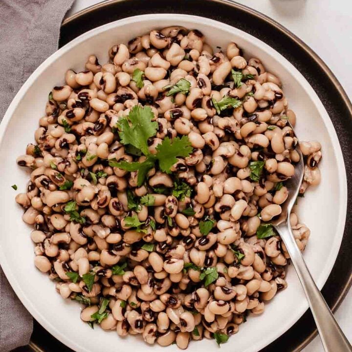 Overhead shot of black eyed peas on white plate with black plate underneath.