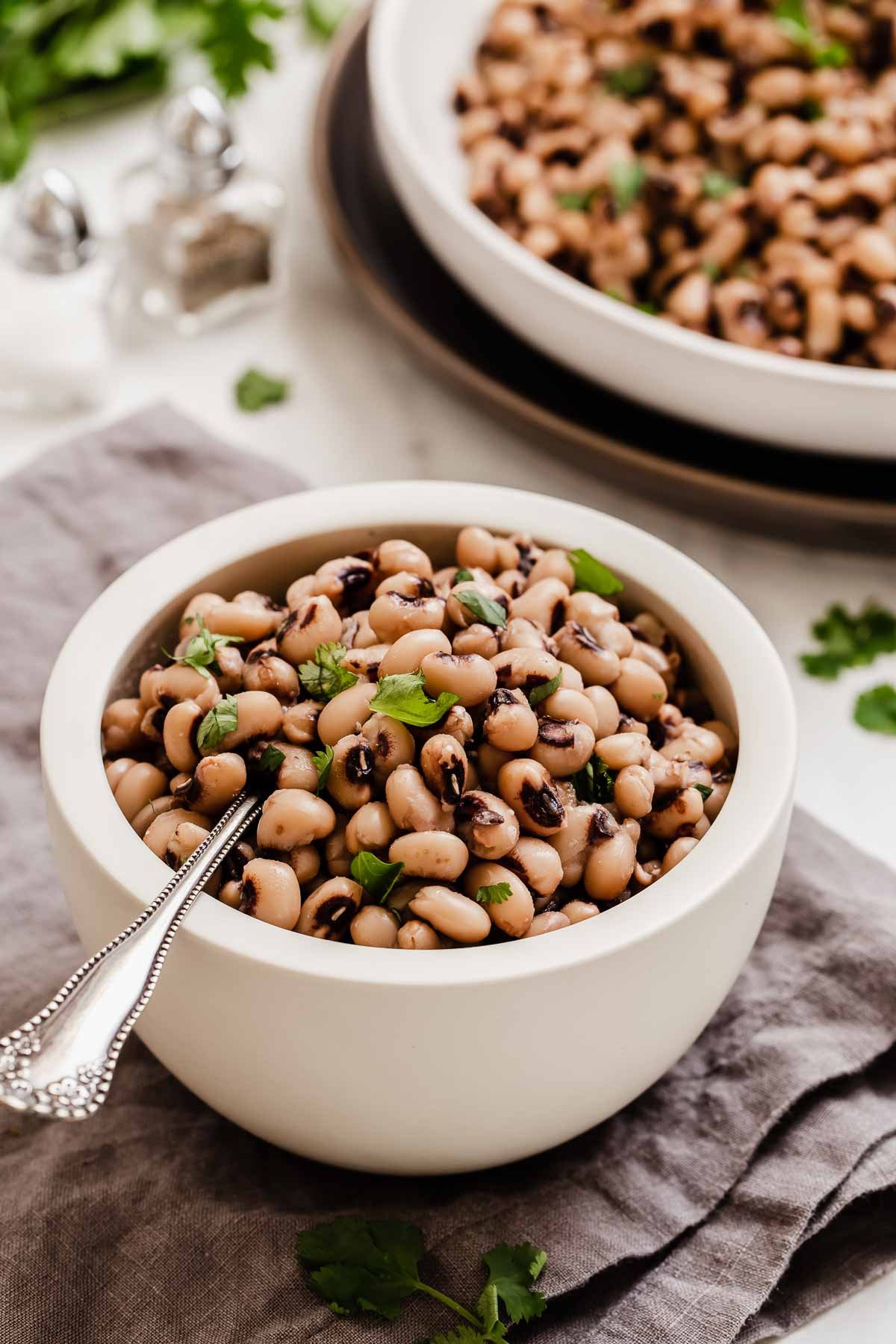 Small white bowl of black eyed peas with spoon sticking out.