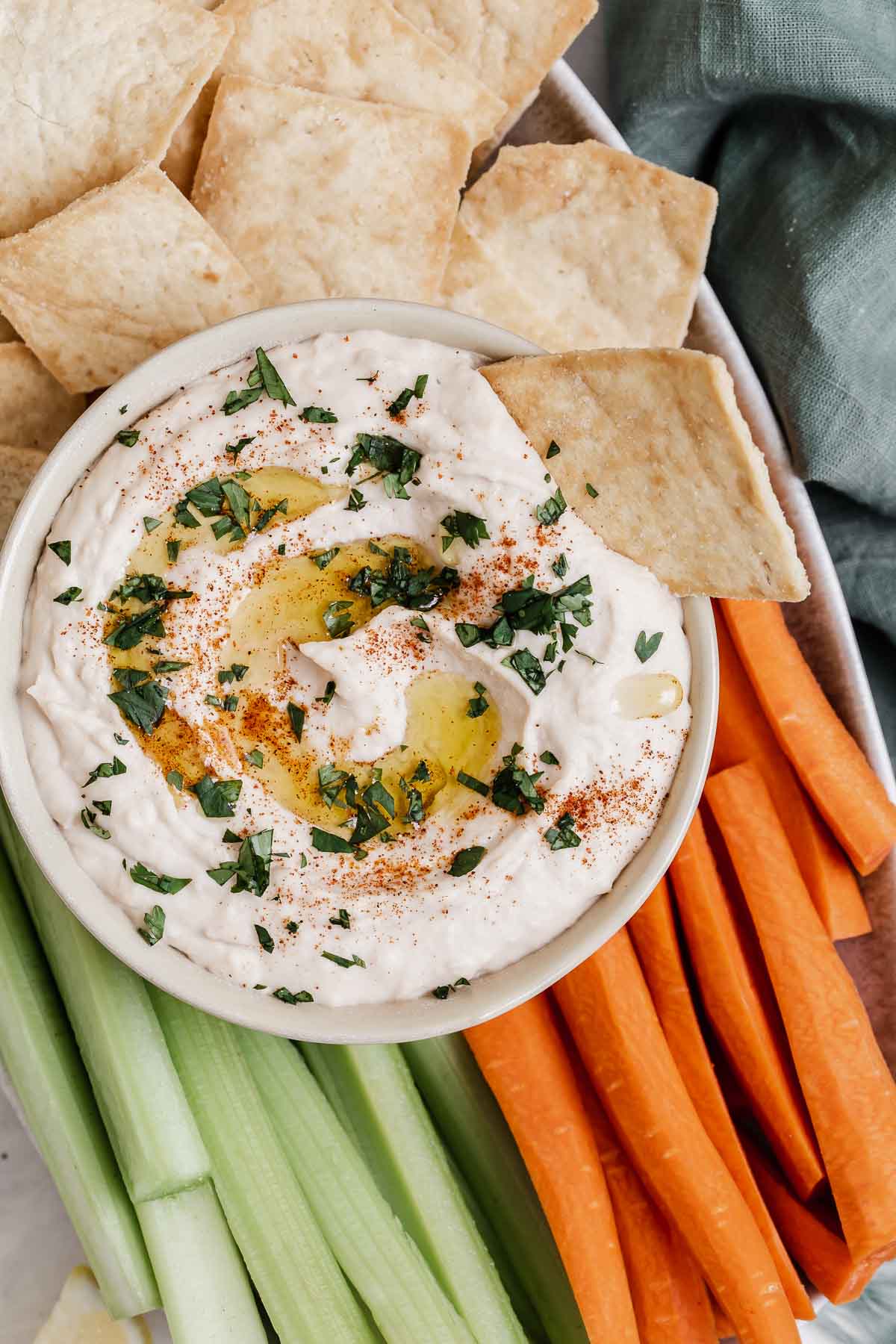 Overhead shot of white bean hummus with carrot, celery and pita chips.