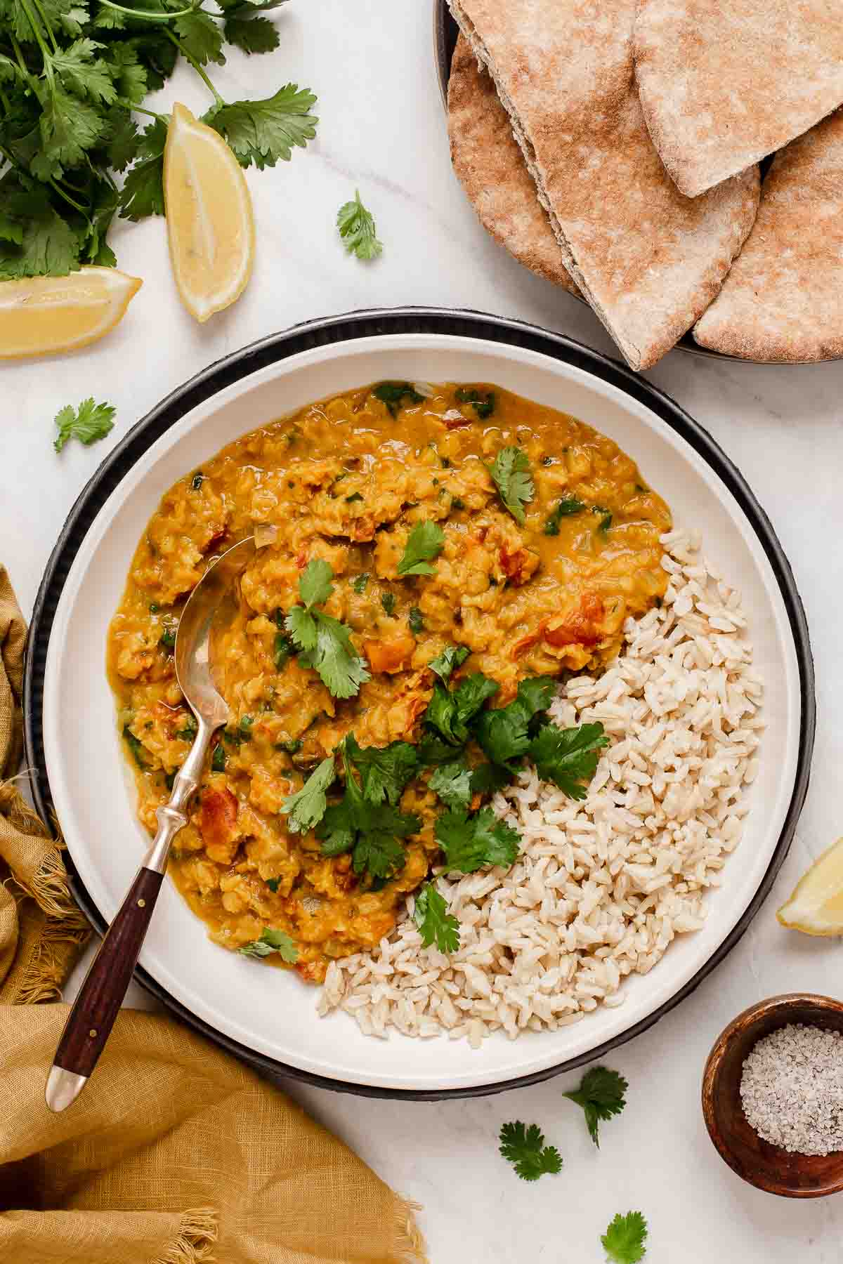Bowl with yellow moong dal and rice topped with cilantro and a fork.