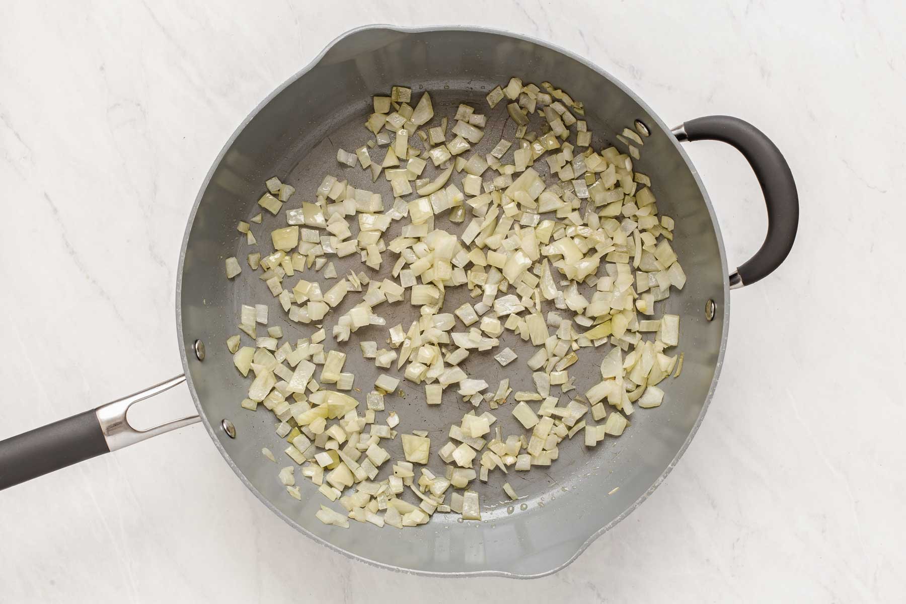Diced onion being sauteed in grey skillet.