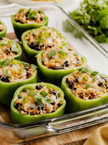 Glass dish of green bell peppers stuffed with beans, rice and cheese.